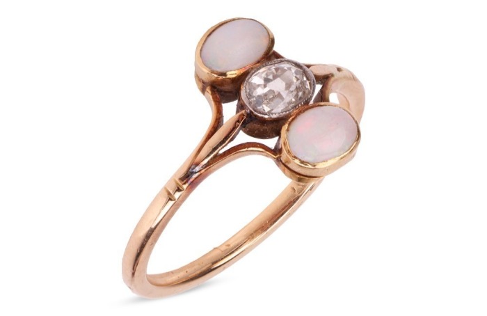 An old brilliant-cut diamond and opal dress ring, centred with an oval old-cut diamond with an approximate weight of 0.30ct, in millgrained collet flanked by two precious opal oval cabochons, between trifurcated shoulders leading to shank in yellow metal 