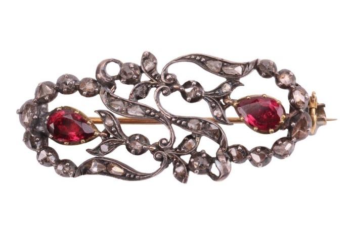 An Early to Mid-19th century gem-set brooch, of floral design; the openwork surround with stylised foliate and flowerheads, set with rose-cut diamond points, highlighted with two pear-cut pink paste in cut-down mounts, brooch fittings to the reverse with 