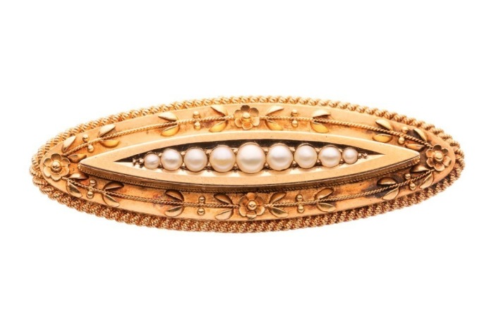 A Victorian seed pearl brooch in 15ct yellow gold, of floral design, the elongated navette-shaped mount centred with a row of graduated split pearls, surround adorned with flower details, and a twisted rope border, brooch fittings to the back with replace