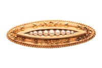 A Victorian seed pearl brooch in 15ct yellow gold, of floral design, the elongated navette-shaped mount centred with a row of graduated split pearls, surround adorned with flower details, and a twisted rope border, brooch fittings to the back with replace