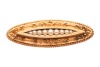 A Victorian seed pearl brooch in 15ct yellow gold, of floral design, the elongated navette-shaped mount centred with a row of graduated split pearls, surround adorned with flower details, and a twisted rope border, brooch fittings to the back with replace