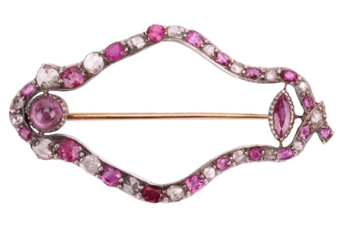 A ruby and diamond-set openwork navette brooch, composed of a row of alternating ruby and rose-cut diamonds (with four later-added synthetic rubies), of navette form, in cut-down white metal mounts, with two additional rubies set to the inside of the ruby