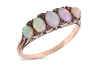 An opal-set half hoop ring; set with five precious opal cabochons, of graduated sizes, each displaying vivid play of colour on a light ground, accented with small polki diamonds, with one diamond deficit, the gallery of scroll design leading to an unmarke