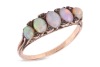 An opal-set half hoop ring; set with five precious opal cabochons, of graduated sizes, each displaying vivid play of colour on a light ground, accented with small polki diamonds, with one diamond deficit, the gallery of scroll design leading to an unmarke