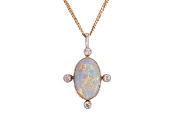 An opal-set pendant, composed of an oval-shaped precious opal cabochon, displaying strong spectral play of colour to a white background, measuring approximately 14mm x 9mm, in a bezel setting with millegrain detailing, accented by bezel-set old-cut diamon