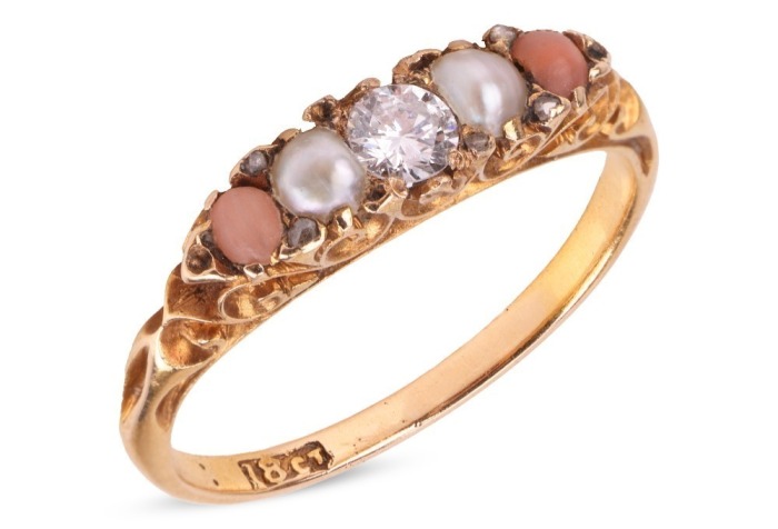 A diamond, pearl and coral half-hoop ring, centred with a round brilliant-cut diamond, flanked by two split pearls and two corallium rubrum cabochons, in a scrolled mount leading to a D-profile shank, in yellow metal stamped '18ct', size L, 2.2 grams. Dia