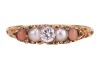 A diamond, pearl and coral half-hoop ring, centred with a round brilliant-cut diamond, flanked by two split pearls and two corallium rubrum cabochons, in a scrolled mount leading to a D-profile shank, in yellow metal stamped '18ct', size L, 2.2 grams. Dia - 2
