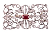 A late Victorian diamond and ruby brooch, of scrolled foliate design, the openwork mount encrusted with old-cut diamonds and rose-cut diamond points, centred with a cushion-cut ruby in collet with twisted cable edge, measures 6.7 x 4.7 mm, unmarked metal 