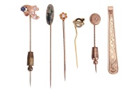 A group of gem-set stick pins; to include an example of an old-cut diamond in buttercup mount, one set with moss agate, another one with rose-cut diamond point, together with a 9ct yellow gold tie clip; total weighable 11.6 grams.