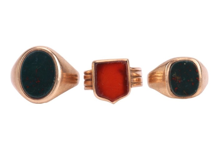 Three signet rings; the first set with an oval bloodstone plaque of 15.3 x 11.5 mm, and another similar example set with a rounded oblong bloodstone plaque of 11.8 x 10.00 mm, both in yellow gold with British hallmarks for 9ct, ring sizes U 1/2 and P, com