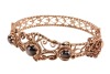 A hinged bracelet set with black star sapphires; the openwork scrolled mount with twisted rope border and beaded accents, set with three graduated oval black star sapphire cabochons, fastens with a tongue clasp with push-in thumbpiece, in yellow metal sta - 4