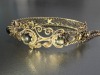 A hinged bracelet set with black star sapphires; the openwork scrolled mount with twisted rope border and beaded accents, set with three graduated oval black star sapphire cabochons, fastens with a tongue clasp with push-in thumbpiece, in yellow metal sta - 6