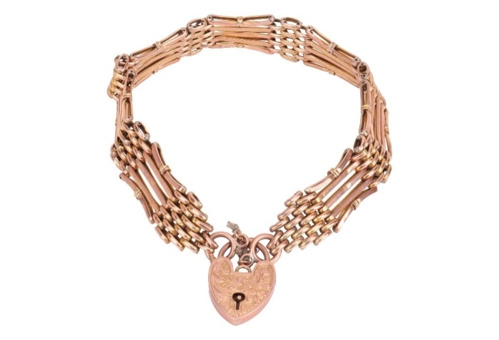 A panther link bracelet with padlock clasp, comprising nine rows of panther links, with textured decorations and slightly curved details, fastens with a heart-shaped padlock clasp with engraved floral scrollwork, marked '9ct', overall length 20.0 cm, 9.6 