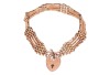 A panther link bracelet with padlock clasp, comprising nine rows of panther links, with textured decorations and slightly curved details, fastens with a heart-shaped padlock clasp with engraved floral scrollwork, marked '9ct', overall length 20.0 cm, 9.6 