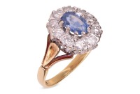 A sapphire and diamond cluster ring in 18ct, centred with an oval-cut sapphire of 6.7 x 4.6 x 3.2mm, encompassed by ten round brilliant-cut diamonds with an estimated total weight of 0.57ct, between foliate shoulders, ring head 1.3 x 1.1 cm, size L, 3.8 g