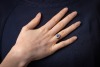 A sapphire and diamond cluster ring in 18ct, centred with an oval-cut sapphire of 6.7 x 4.6 x 3.2mm, encompassed by ten round brilliant-cut diamonds with an estimated total weight of 0.57ct, between foliate shoulders, ring head 1.3 x 1.1 cm, size L, 3.8 g - 5