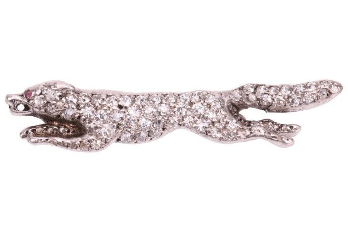 A diamond-set fox brooch, sculpted as a running fox, fully encrusted with single-cut diamonds, with a ruby cabochon as eye, later brooch fittings to the reverse, unmarked white metal surface testing as 18ct, 4.0 cm wide, 4.1 grams. Please note: Unless oth