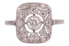 An Art Deco style panel ring, centrally-set with a bezel-set round brilliant diamond, within a diamond-set openwork panel, to a white metal shank marked &lsquo;plat&rsquo;, size N; 3.3 grams. - 2