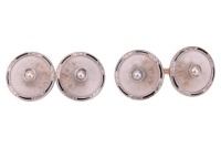 Krementz - a pair of rock crystal and split pearl cufflinks; the round and frosted rock crystal panels with carved radiating patterns, in a millgrained frame with foliate and black enamel details, centred with an applied split pearl, bar link connections 