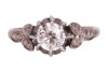 A late Art Deco diamond solitaire ring, centred with an Old-European cut diamond of 5.6 mm, estimated weight 0.70ct, in a buttercup mount between foliate shoulders, white metal stamped '18ct PLAT', size M&frac12;, 3.4 grams. Diamond approximately measures 5.6 x - 2