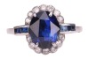 A sapphire and diamond cluster ring; the oval mixed-cut sapphire claw mounted within a border of fourteen round brilliant cut diamonds, with two calibr&eacute; cut sapphires to each shoulder. Plain D-shaped shank, unmarked, shank surface testing as 14ct and moun - 2