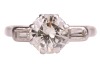 A diamond solitaire ring, the central diamond measuring approximately 7.5mm, with an estimated carat weight of 1.70ct, flanked by two bezel-set baguette-cut diamonds, in a bi-colour metal mount marked &lsquo;18ct&rsquo;, size L; 3.8 grams. - 2