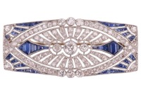 An Art Deco sapphire and diamond-set brooch, of architectural design; the rounded rectangular openwork frame centrally-set with three old-cut diamonds, with millegrain bezel surround, the largest diamond measuring approximately 4.5mm, within a navette-sha