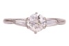 A diamond-set ring, composed of an old European cut diamond in a six-prong setting, measuring approximately 5.7mm with an estimated carat weight of 0.70ct, flanked by two tapered baguette-cut diamonds, to an 18ct white gold mount, size L; 2.5 grams - 2