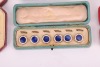 A matched gold, mother-of-pearl and sapphire dress set, in fitted case; together with a pair of silver, mother-of-pearl and enamel cufflinks, adapted from buttons, with later links; two sets of six gilt metal and enamel buttons in fitted cases, circa 1910 - 4