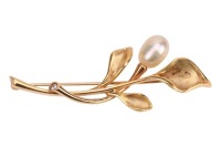 A pearl-set spray brooch, the stylised flowerheads with a sandblast finish, mounted with a potato-shaped cultured pearl of 7.4 mm, stem finial flush-set with a round brilliant-cut diamond accent, brooch fittings to the reverse, yellow metal stamped '750',