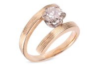 A diamond solitaire ring, of Modernist-style crossover design, composed of a round brilliant diamond measuring approximately 7.25mm with an estimated carat weight of 1.49ct, in a six-prong setting, to a crossover mount, with textured design, hallmarked 18