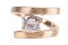 A diamond solitaire ring, of Modernist-style crossover design, composed of a round brilliant diamond measuring approximately 7.25mm with an estimated carat weight of 1.49ct, in a six-prong setting, to a crossover mount, with textured design, hallmarked 18 - 3