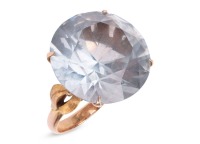 A large synthetic spinel dress ring; set with a round synthetic spinel in pale blue, claw set to a yellow metal mount with floral motif shoulders, to a tapered D-profile shank, marked as '14k', ring head measures 1.9 cm across, ring size M&frac12;, total weight 
