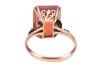 A synthetic orange sapphire ring, with an emerald-cut synthetic sapphire in reddish-orange colour, double claw set on a yellow metal mount, floral details on gallery and shoulders, to a D-profile shank, marked '14k', ring size O, total weight of item 4.8 - 4