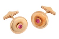 A pair of ruby-set cufflinks, of polished disc form, each centred with an applied round ruby cabochon, toggle fittings to the back, yellow metal stamped '750', signed Serkos and in respective branded case, 1.6 cm wide, 12.5 grams.