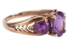 An amethyst trilogy ring, centred with an oval-cut amethyst flanked by further two pear-cut amethysts, with pierced chevron shoulders to tapering shank, in yellow metal stamped '9K', size K, 2.1 grams. - 3