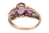 An amethyst trilogy ring, centred with an oval-cut amethyst flanked by further two pear-cut amethysts, with pierced chevron shoulders to tapering shank, in yellow metal stamped '9K', size K, 2.1 grams. - 4