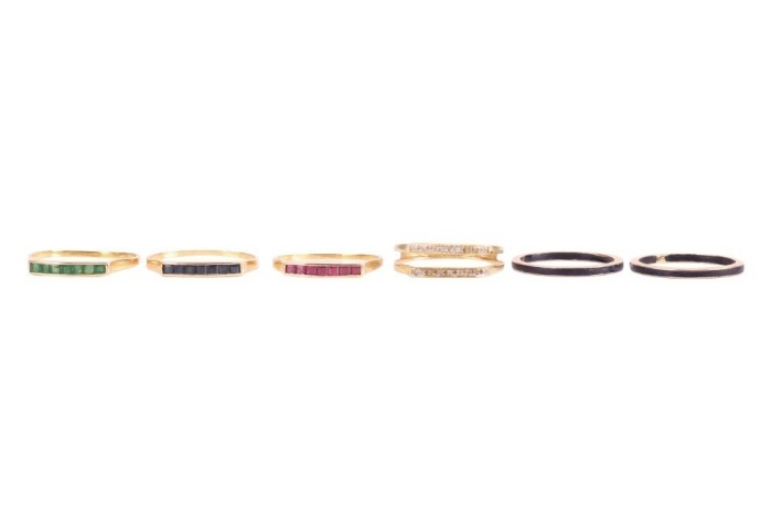 A small group of rings comprising three matching seven-stone rings, each channel-set with calibre-cut gemstones including rubies, emeralds and sapphires, to yellow metal mounts surface tested as 14ct, size U, together with an interchangeable gem-set outer