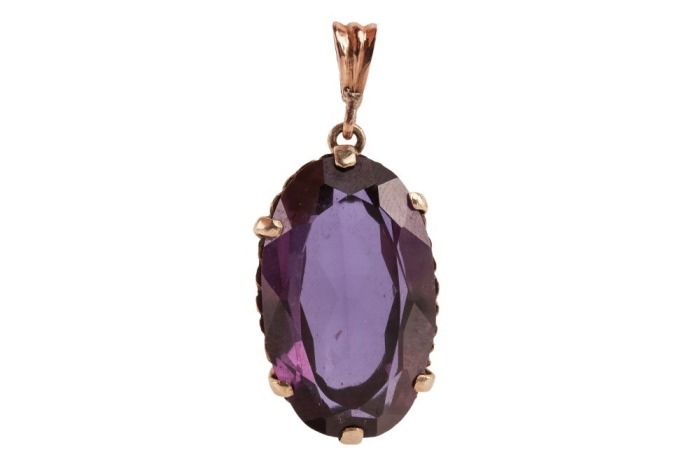 A large synthetic colour change sapphire pendant, claw-set to a reeded mount, on a tapered bail, unmarked metal surface testing as 9ct, 3.7 cm drop, 9.6 grams. Please note: Unless otherwise stated, lots have been tested using an electronic tester. This is