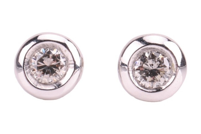 A pair of diamond-set stud earrings, composed of round brilliant diamonds, with an estimated total carat weight of 0.34ct, bezel-set in 18ct white gold mounts, the unassociated white metal earring backs marked &lsquo;9K&rsquo; and the other &lsquo;925&rsquo;; 2.1 grams