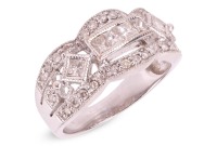 An Art Deco style diamond-set ring, centrally set with a row of four princess-cut diamonds, flanked by an additional two bezel-set princess-cut diamonds, between two scalloped rows of round brilliant-cut diamonds, to a white metal mount marked &lsquo;18K&rsquo; and &lsquo;