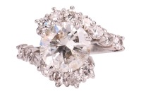 A diamond-set crossover-style ring, featuring a central round brilliant diamond, measuring approximately 9.1mm x 5.2mm, with an estimated carat weight of 3.00ct and an estimated colour and clarity grade of J/K and I2, the crossover-style shoulders each cl