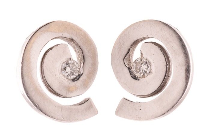 A pair of diamond-set stud earrings in the form of swirls, centrally adorned with a round brilliant-cut diamond accent, screw-back fittings to reverse, white metal bearing Russian assay marks for 14ct, 1.0 cm wide, 2.0 grams.