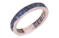 A sapphire eternity ring, featuring twenty-two square and calibre-cut blue sapphires channel-set in white metal surface testing as platinum (insert to back of ring surface testing as base metal), size P, 3.03 grams. Please note: Unless otherwise stated, l
