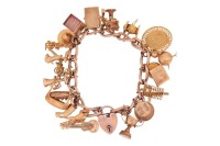 A 9ct gold charm bracelet, suspending twenty four charms, mostly 9ct gold, but including 14ct and 18ct examples; gross weight: 87.5 grams