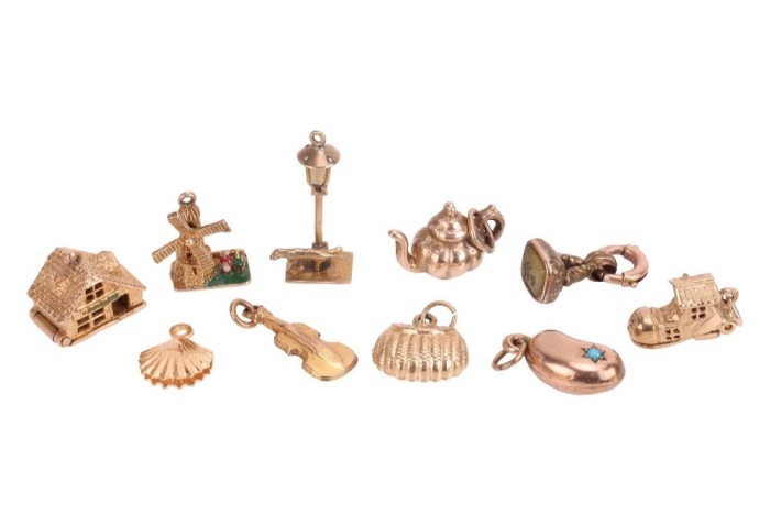 A group of yellow metal charms, to include a 9ct yellow gold articulated house charm, a 9ct gold violin charm, a 9ct gold articulated shoe charm, a 9ct gold handbag charm, the four weighing 6.5 grams; as well as a teapot and a bean charm, both marked 9ct 