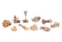 A group of yellow metal charms, to include a 9ct yellow gold articulated house charm, a 9ct gold violin charm, a 9ct gold articulated shoe charm, a 9ct gold handbag charm, the four weighing 6.5 grams; as well as a teapot and a bean charm, both marked 9ct 