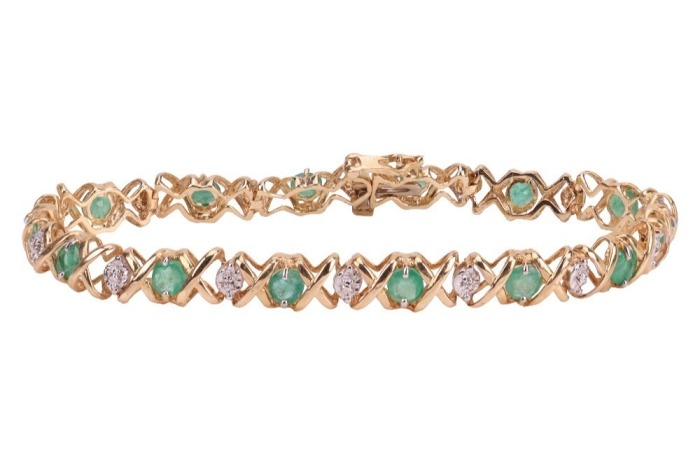 An emerald line bracelet, comprising fourteen round-cut emeralds, interspersed by stylised cross forms and a white-metal illusion panel, every other white metal panel illusion-set with a rose-cut diamond, measuring 18.0cm in length, completed with an inte