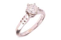 A diamond solitaire ring, comprising a central round brilliant-cut diamond in a six claw setting, with an estimated carat weight of 0.83ct, to tapering shoulders with circular drilled detail, to an 18ct white gold knife-edge band, size N, 4.9 grams.