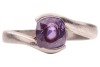 A purple sapphire crossover ring, featuring a cushion-cut purple sapphire of 7.1mm x 6.1mm x 4.5mm, set between bypass shoulders leading to a tapering shank, unmarked white metal testing as platinum, size N&frac12;, 6.4 grams. Accompanied by a Stalwart gem repor - 2